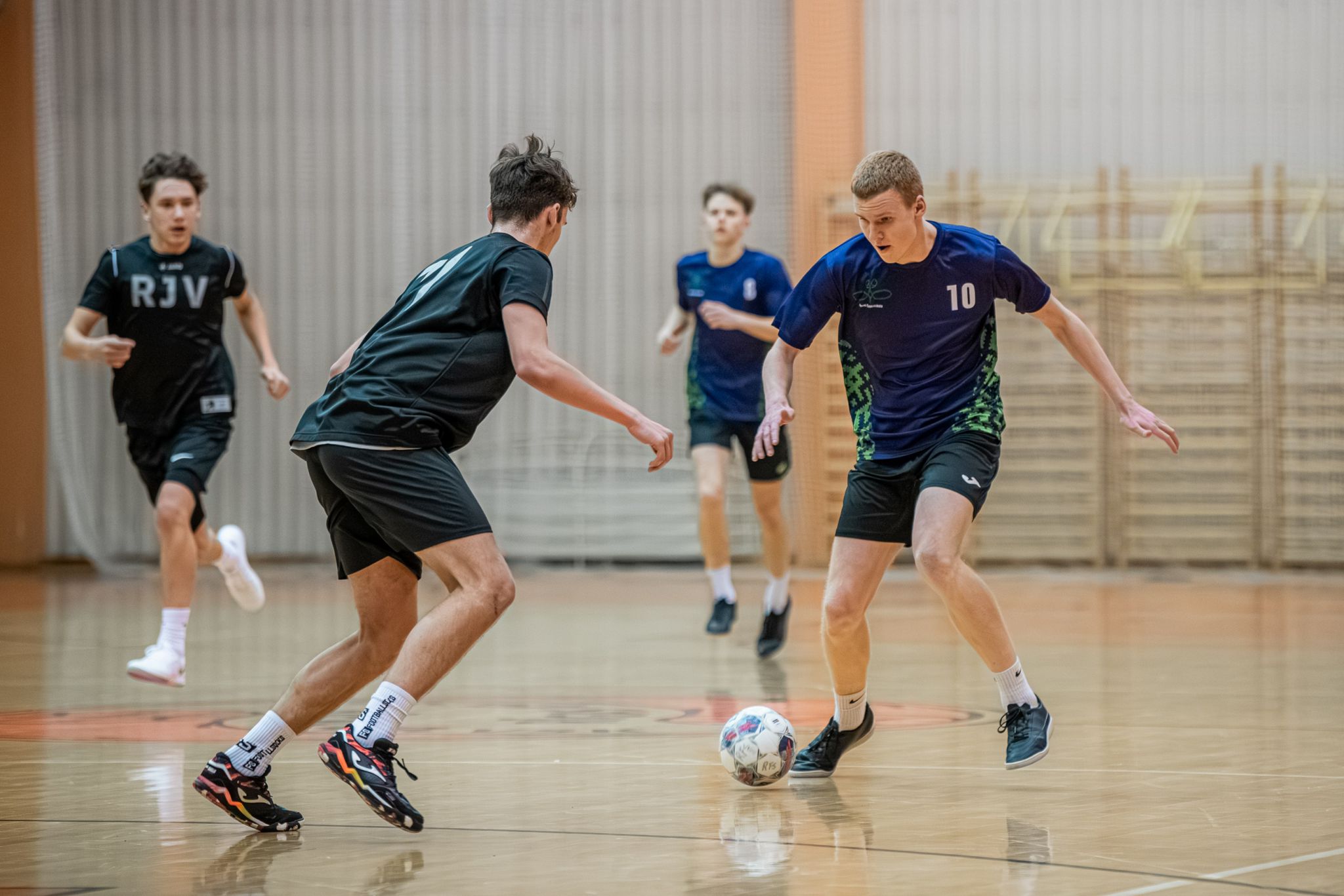 jainieši zilos krekliņos izspēle futbolā bumbu.