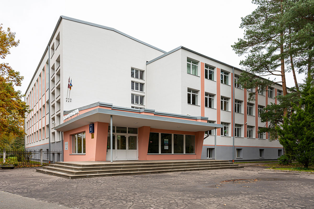 Skolas galvenē ieeja, balsta ēka ar sarkanīgu ieeju.