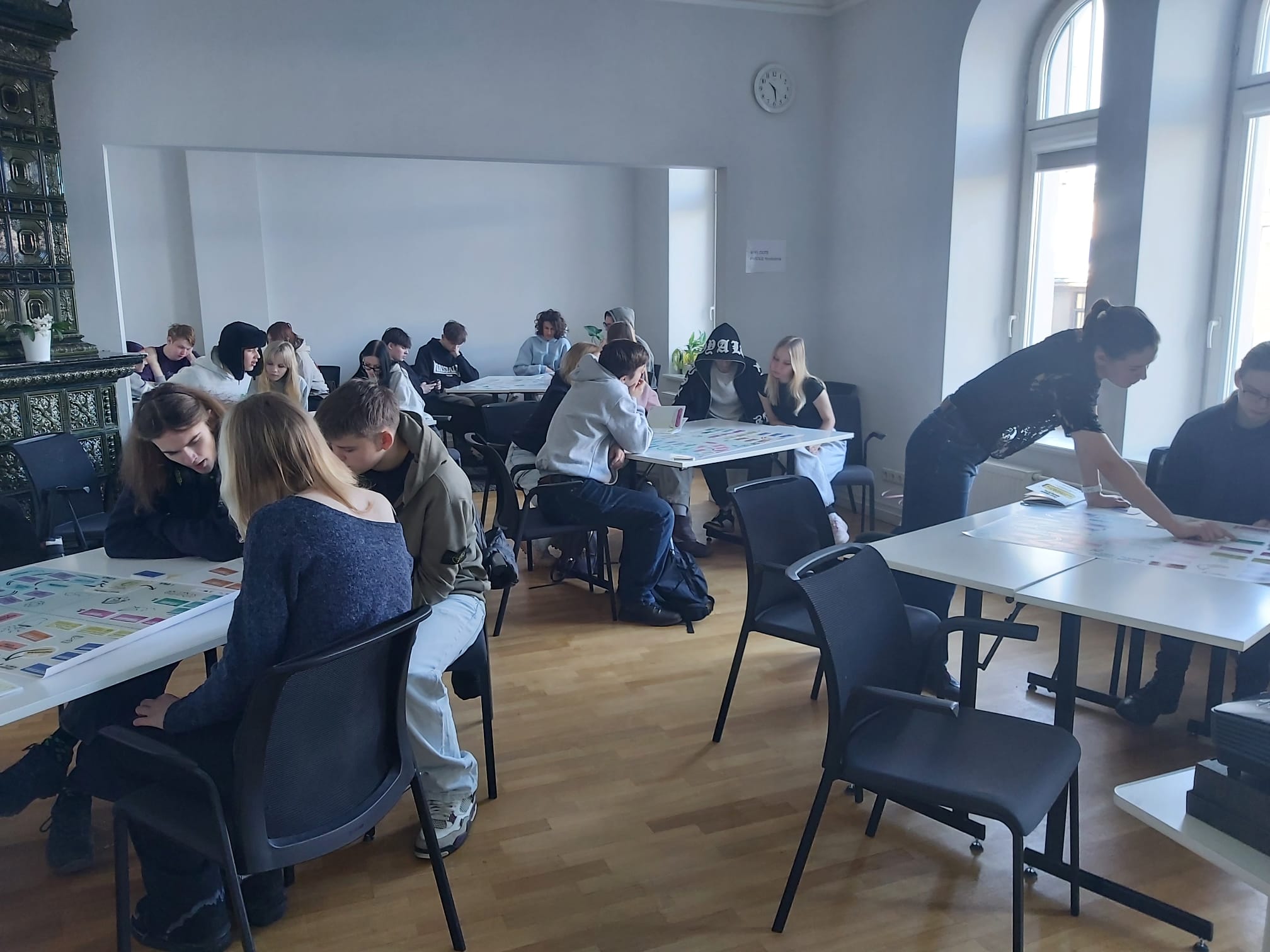 10.a un 10.b klases apgūst pirmos soļus sociālajā uzņēmējdarbībā -jaunieši sēž pie galdiem un pēta