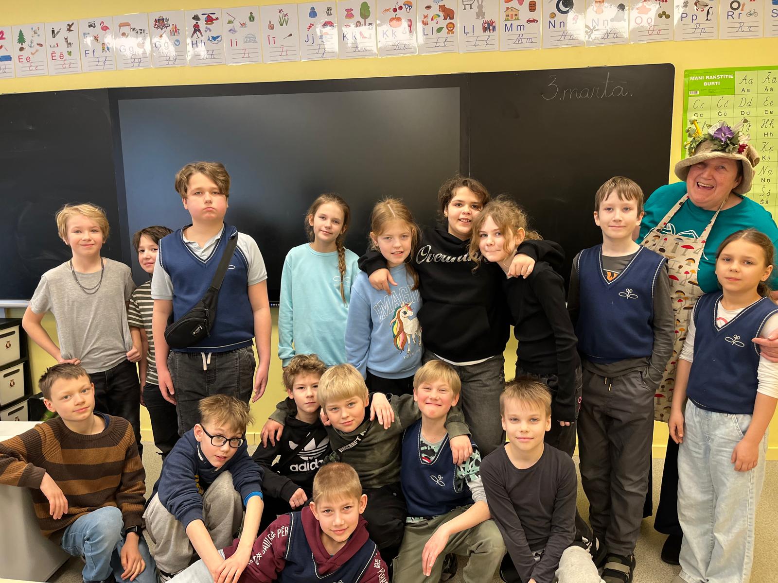 Skolēni sastājūšies klasē pie elektroniskās tāfeles, daži stāv, daži sēž!