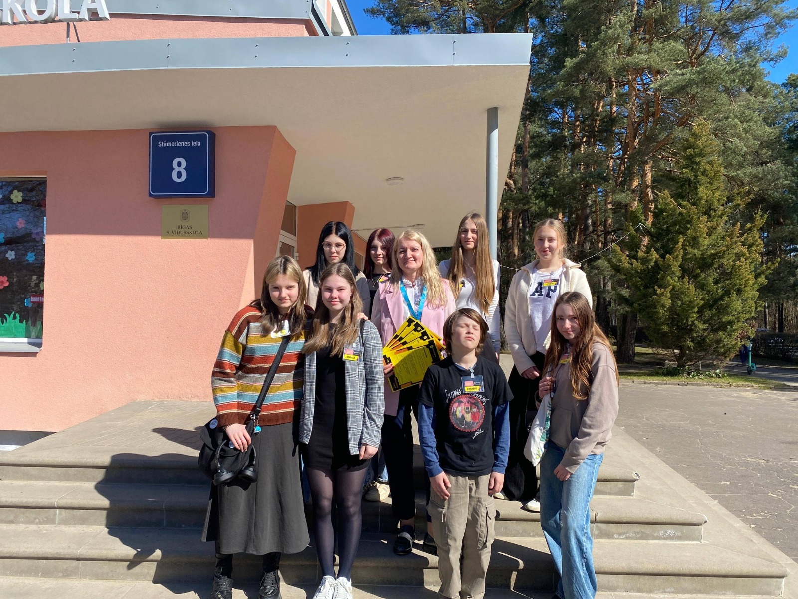 Vairāki skolēni stāv pie skolas fasādes, tie ir ēnu dienas dalībnieki